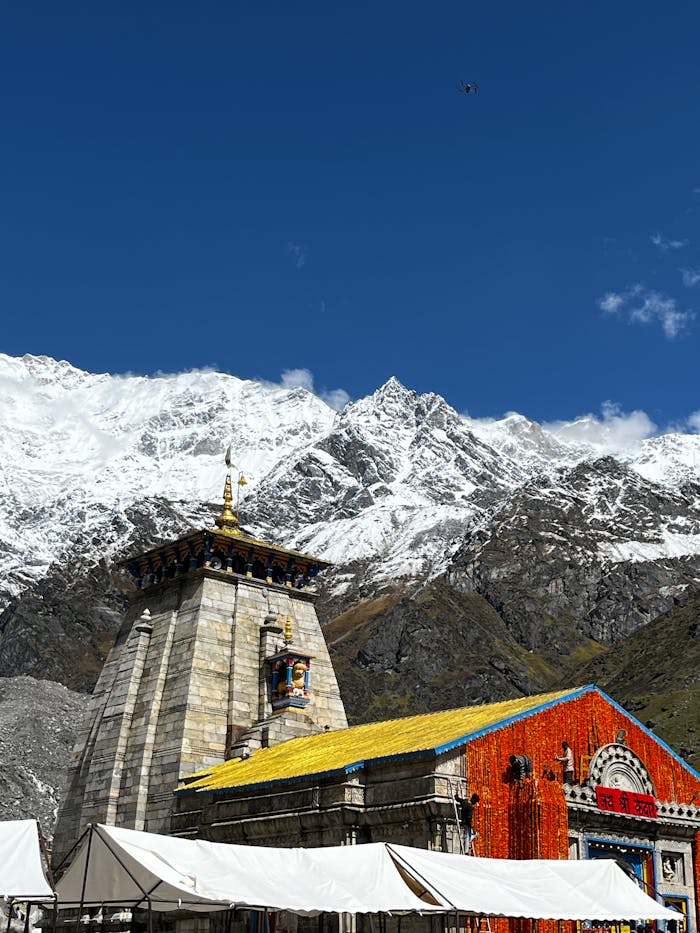 who-we-are Majestic view of Kedarnath Temple against snow-capped Himalayan peaks under clear blue sky.