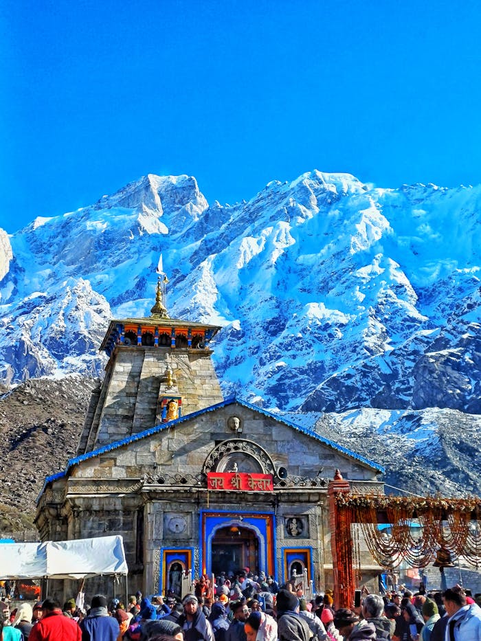 journey Historic Kedarnath Temple amidst stunning snow-capped Himalayan peaks on a clear day.
