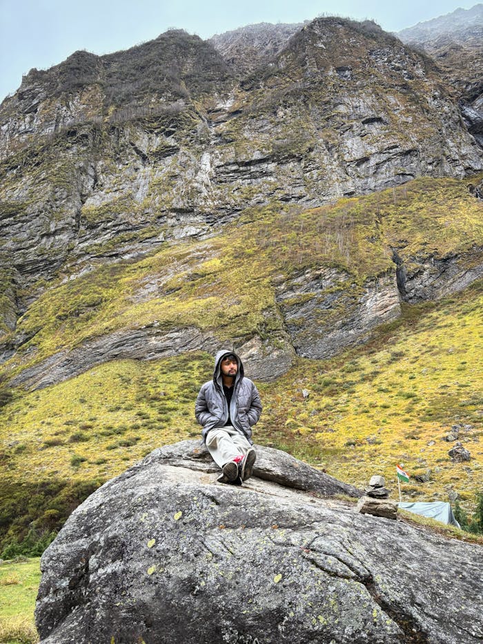 Solitary hiker on a rock in Badrinath, Uttarakhand, India with towering mountains all around.
