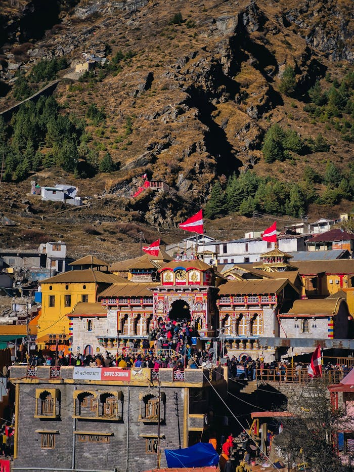 Colorful Badrinath Temple nestled in the majestic Himalayas with vibrant flags waving.